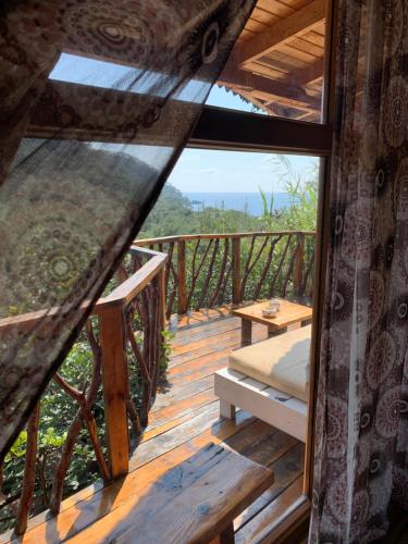 a room with a balcony with a bed and a table at Bamboo Bungalow with Sea View in Kabak Bay, Ölüdeniz in Fethiye