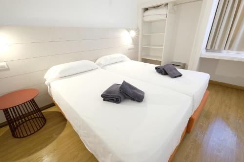 Dos camas en una habitación con dos zapatos negros. en MAKĀI Bungalows, en Playa del Águila