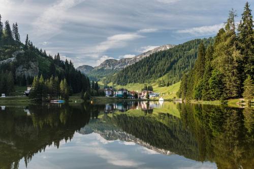 a lake in the middle of a valley with trees at Hotel Salzburger Hof Zauchensee in Zauchensee