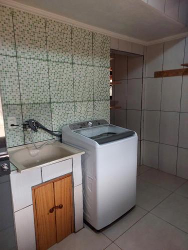 baño pequeño con lavadora y lavamanos en Casas Bueno en Camanducaia