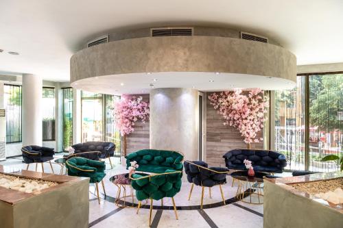 a lobby with green chairs and tables and flowers at Zdravets SPA Hotel in Velingrad