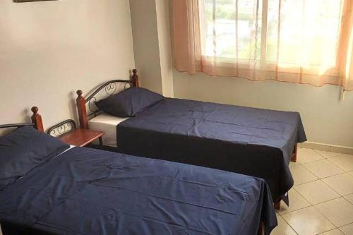 1 Schlafzimmer mit 2 Betten mit blauer Bettwäsche und einem Fenster in der Unterkunft Le jaune d'Ifni in Agadir