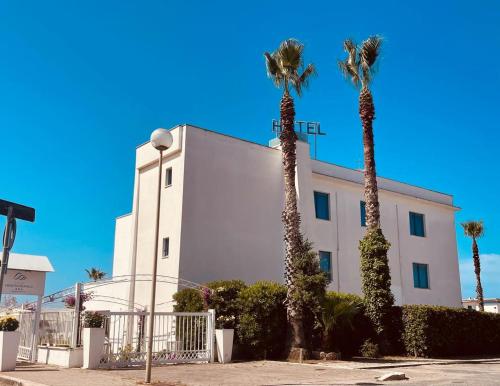 a white building with palm trees in front of it at Hotel Mediterraneo in Lido di Latina 