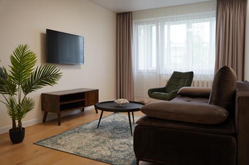 een woonkamer met een bank, een stoel en een tv bij Sonata apartment in Panevėžys