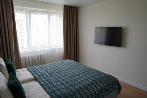 a bedroom with a bed and a flat screen tv at Sonata apartment in Panevėžys