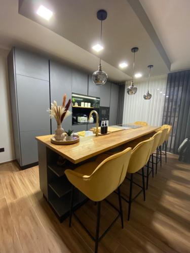 una cocina con una gran mesa de madera y sillas amarillas en Marsalforn luxurious Apartment, en Marsalforn