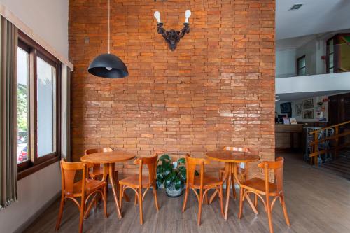 a dining room with wooden tables and chairs and a brick wall at Hotel Dom Rafael Express in Santa Maria