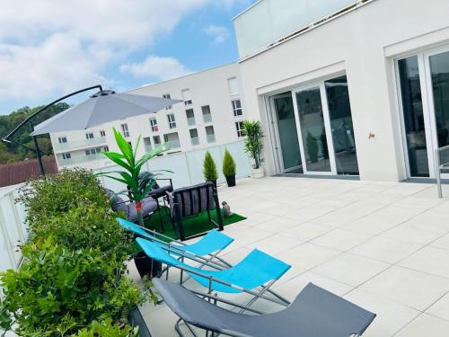 een patio met 2 blauwe stoelen en een parasol bij Bel Appartement avec Terrasse privée 86m2 in Noisy-le-Sec