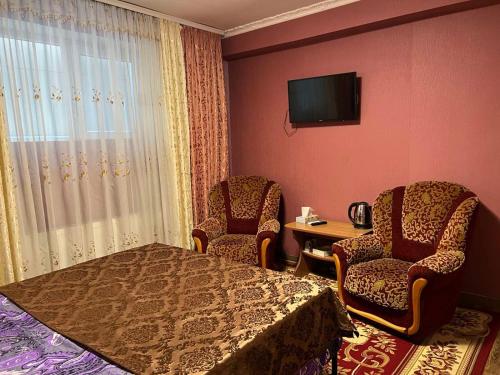 a room with two chairs and a table and a television at Комната Gold Rose in Chişinău