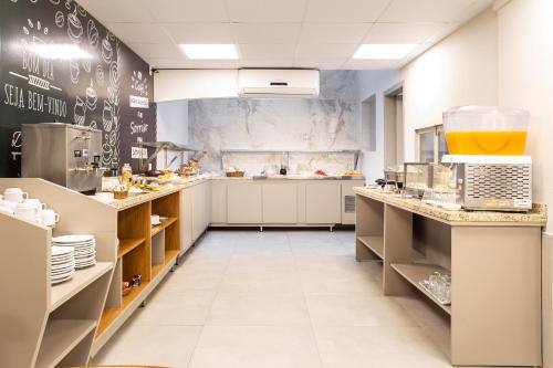 una grande cucina con armadi bianchi e banconi di Hotel Dom Rafael Express a Santa Maria