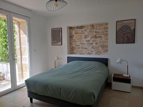 um quarto com uma cama e uma grande janela em Maison de Charme - Maréchalerie - Nîmes em Uchaud