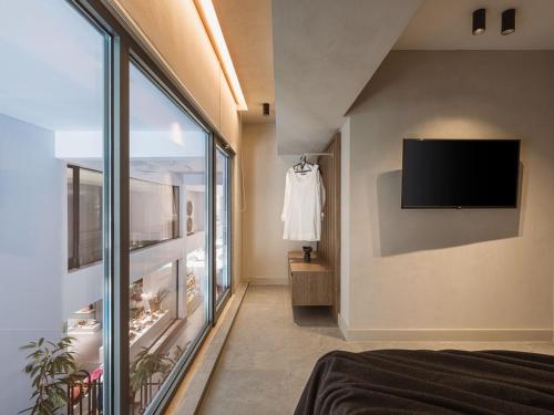 a bedroom with a large window and a tv on the wall at Grand Residences in Chania Town
