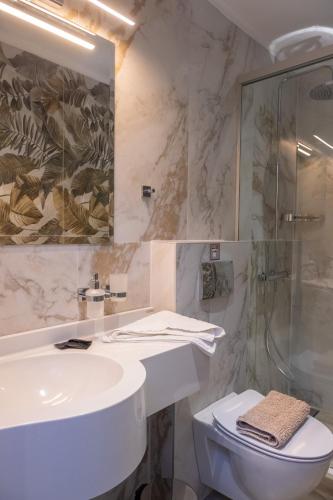 ein Badezimmer mit Waschbecken, Dusche und Toilette in der Unterkunft SEKRETO hotel in Parga