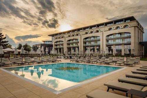 Kings' Valley Medical & Spa Hotel في كازانلوك: تقديم فندق فيه مسبح وكراسي