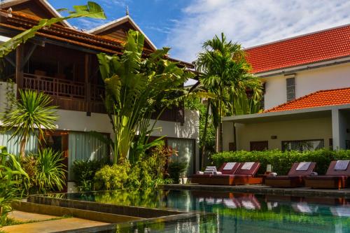 uma piscina em frente a uma casa com cadeiras em Sokkhak Boutique Resort & Spa em Siem Reap