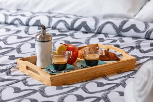 a tray of food with two drinks and apples on a bed at Divi Apartments Milano - Strategic Place in Milan