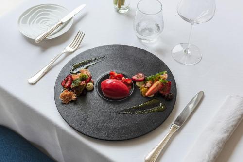 a black plate of food on a white table at Domaine du Limonay, The Originals Collection in Saint-Méloir-des-Ondes
