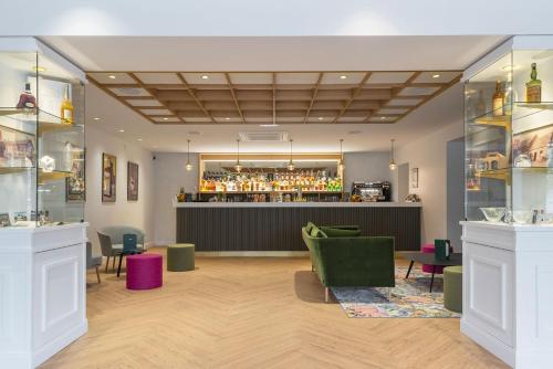 a lobby with a bar with green chairs at Domaine du Limonay, The Originals Collection in Saint-Méloir-des-Ondes