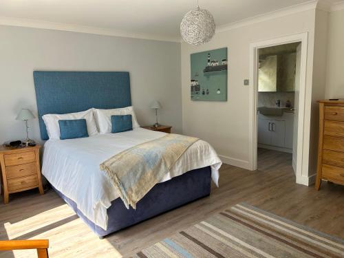a bedroom with a large bed with a blue headboard at Conifers in Lyme Regis