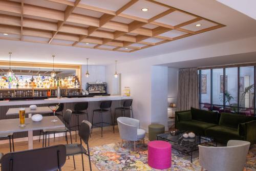 a living room with a bar with a green couch at Domaine du Limonay, The Originals Collection in Saint-Méloir-des-Ondes