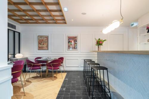 a bar with purple chairs and a table in a room at Domaine du Limonay, The Originals Collection in Saint-Méloir-des-Ondes