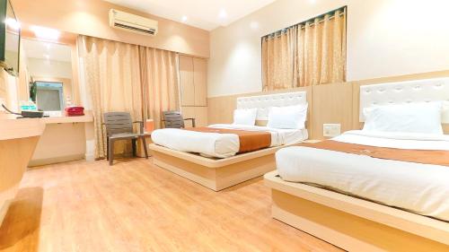 a hotel room with two beds and a desk at Hotel Yog Palace Newly Renovated in Shirdi