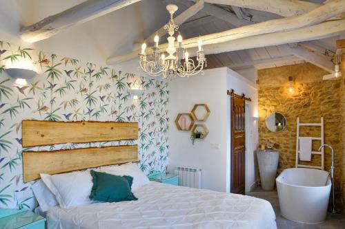 a bedroom with a bed and a chandelier and a tub at Casa ENTREPIEDRAS in Villalís