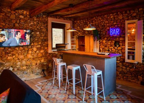 un bar con taburetes y TV en una pared de piedra en ENTREPIEDRAS, 
