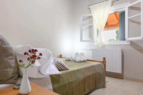 a bedroom with a bed with a vase of flowers on it at Notus Vacation House in Lefkímmi