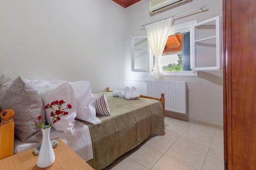 a bedroom with a bed and a vase of flowers on a table at Notus Vacation House in Lefkímmi