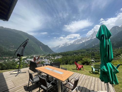 a wooden deck with a table and chairs and mountains at Amazing View appartement du Chalet in Les Houches