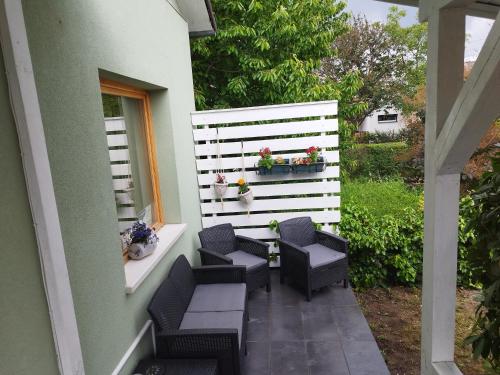 eine Terrasse mit Stühlen und einem weißen Zaun in der Unterkunft SUSAN Apartman in Hajdúszoboszló