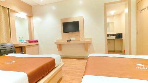 a hotel room with two beds and a tv at Hotel Yog Palace Newly Renovated in Shirdi