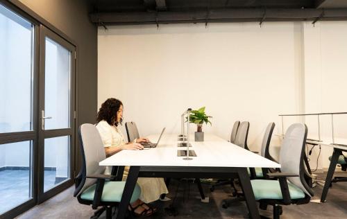 a woman sitting at a table with a laptop at Coliving Compostela in Santiago de Compostela