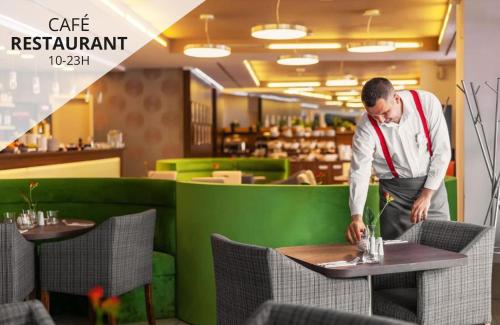 Un uomo in piedi a un tavolo in un ristorante di Iris Hotel Eden - Czech Leading Hotels a Praga