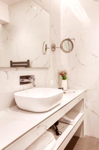 a white bathroom with a sink and a mirror at DAYS City Suites Athens in Athens