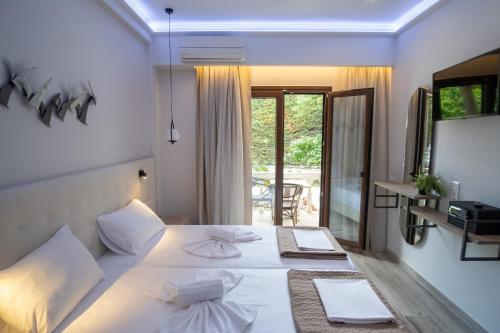 ein Schlafzimmer mit einem weißen Bett und einem Balkon in der Unterkunft SEKRETO hotel in Parga