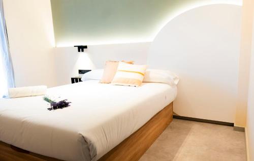 Un dormitorio con una cama blanca con una flor. en Coliving Compostela, en Santiago de Compostela