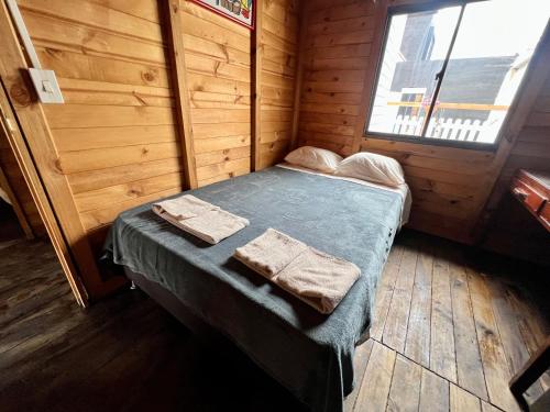 a bed in a wooden room with towels on it at Cabaña Gran torino cajica in Cajicá