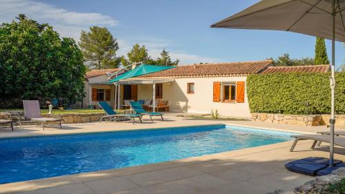 una piscina con sillas y una sombrilla junto a una casa en Mon Ginesté, en Flayosc