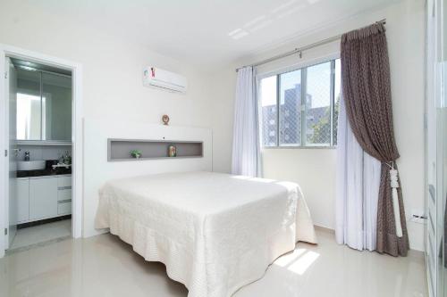 Un dormitorio blanco con una cama blanca y una ventana en Aluguel Apartamento 2 quartos c/ 1 suíte | Bombas/SC, en Bombinhas