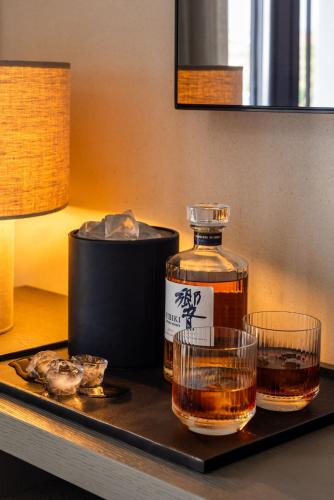 a bottle of whiskey and two glasses on a tray at Noima Boutique Hotel Mykonos in Agios Ioannis Mykonos