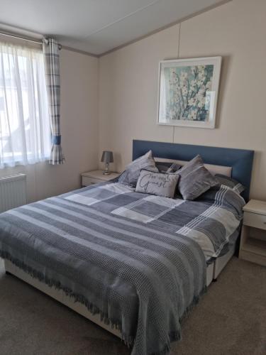 um quarto com uma cama grande e um cobertor azul em Luxury 6 berth lodge at Quince 10 em Ferndown