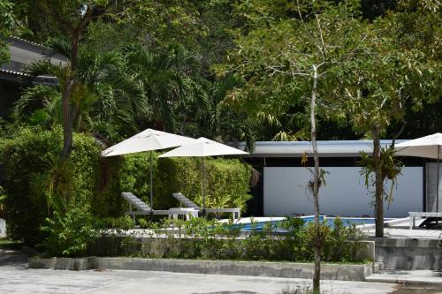 a patio with two chairs and an umbrella and a pool at The Zohan Resort & Travel Agency in Wok Tum
