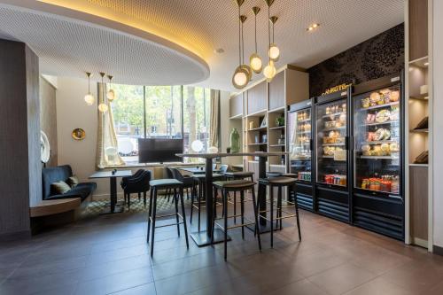 un restaurant avec un bar avec des tabourets et des tables dans l'établissement Novotel Suites Paris Expo Porte de Versailles, à Paris