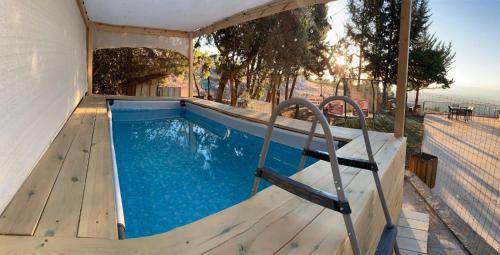een banenzwembad met een houten terras en blauw water bij וילה פינתית עם נוף פאנורמי לכנרת in Nof Kinneret