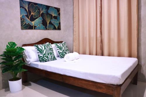 uma cama com lençóis brancos e uma planta num quarto em El Nido U Inn em El Nido