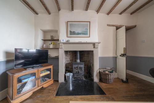 a living room with a television and a fireplace at Bank House | Peak District in Longnor