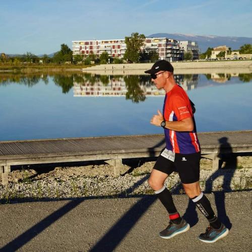 a man running on a road near a body of water at Provence, Studio climatisé, vue lac Spirou 400 metres, Avignon 15 mn in Monteux