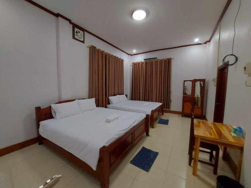 a bedroom with two beds and a table in it at Inthavong Hotel/Guest House in Vang Vieng